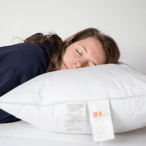 A woman sleeping on a Holiday Inn® Soft Support Pillow with a label by Hollander.