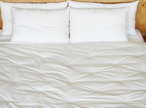 A Holy Lamb Organics Wool Comforter - Cool Comfort on a bed.