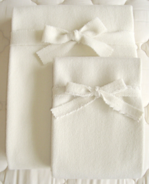 A white blanket with a bow made of Holy Lamb Organics Wool Moisture Barriers.