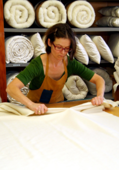 A woman cutting fabric for Holy Lamb Organics Wool Moisture Barriers.