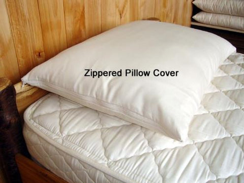A Holy Lamb Organics Zippered Pillow Protector made of organic cotton on top of a wooden bed.