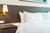 A white bed with a Pillow Factory 75/25 Gray Duck Feather & Down Pillow in a hotel room.