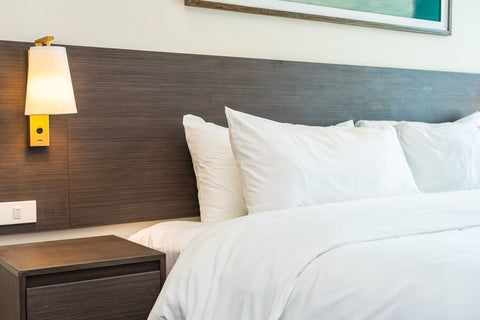 A white bed with a Pillow Factory 75/25 Gray Duck Feather & Down Pillow in a hotel room.