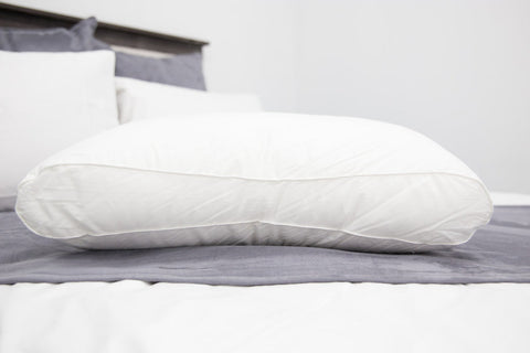 A Hollander Holiday Inn® Firm Support Polyester Pillow Combo Pack (Includes 2 Pillows) for side sleepers on the bed.