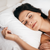 A woman sleeping peacefully in bed with her eyes closed on the Keeco Holiday Inn® Infinity Pillow | Extra-Firm Support.