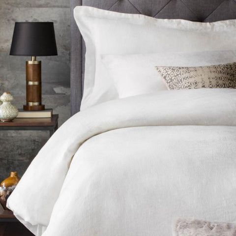 A bed with Malouf French Linen Duvet Set and a lamp.