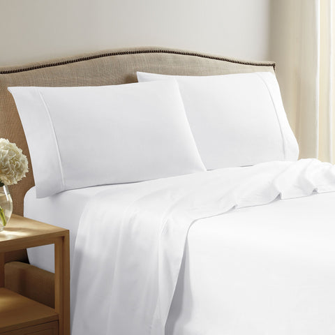 A white bed with white sheets and pillows from the Martex Grand Patrician Collection.