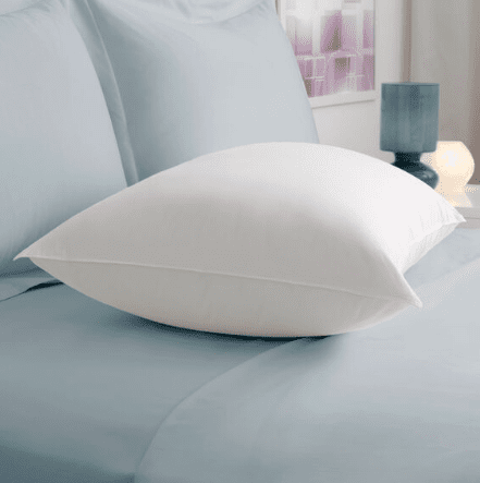 A white Pacific Coast Feather Down Chamber Pillow from Pacific Coast Feather Company on a blue bed offers firm support.