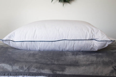 A Pacific Coast Feather DownAround Pillow from Pacific Coast Feather Company is sitting on top of a bed.