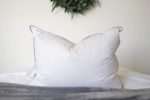 A Pacific Coast Feather DownAround Pillow on top of a bed with a wreath on it.