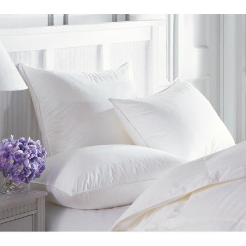A white bed with Pillow Factory Comfort Down pillows and flowers on it.