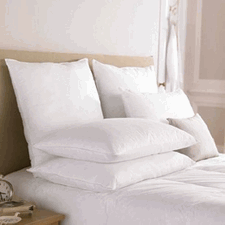 A neatly made bed with white bedding, featuring The Pillow Factory Housekeeper's Choice Gold Pillow | Medium Firmness pillows and a comfortable duvet, inviting a peaceful and restful sleep in a serene bedroom setting.
