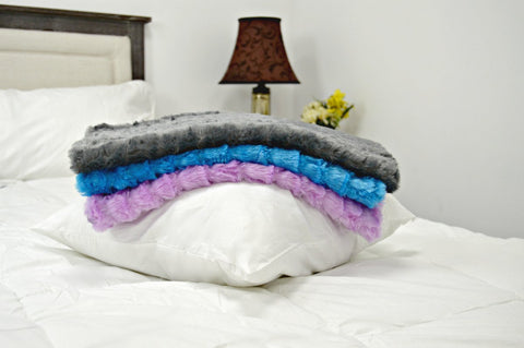Three Pillowtex Plush 18'x18' Throw Pillows with Covers piled on a bed.