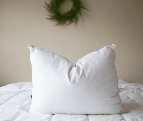 A comfortable white Pillowtex Pillowtex White Duck Down & Feather Pillow | 75% Feather/25% Down on a bed with a wreath on it.