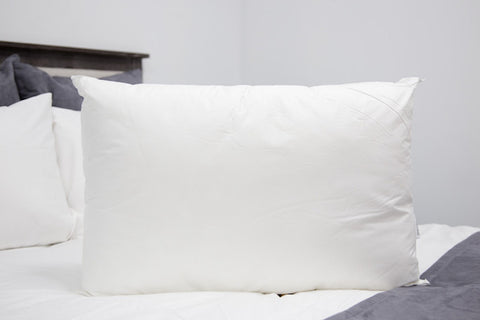 A hypoallergenic white Pillowtex Allerban Polyester Pillow on a bed.