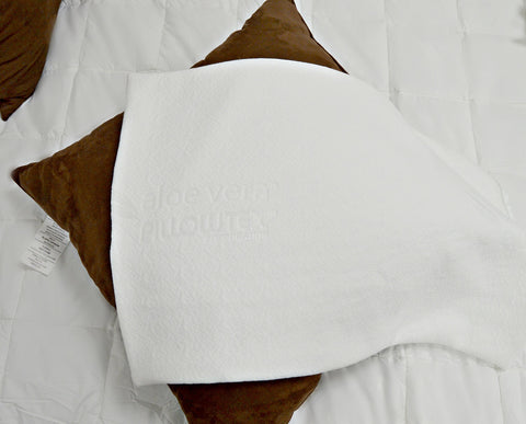 A Pillowtex Aloe Vera Pillow Cover with a zippered closure on a bed.