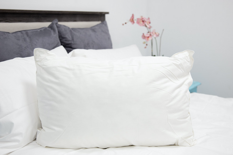 A Firm white Pillowtex Down Alternative Pillow sits on top of a bed.