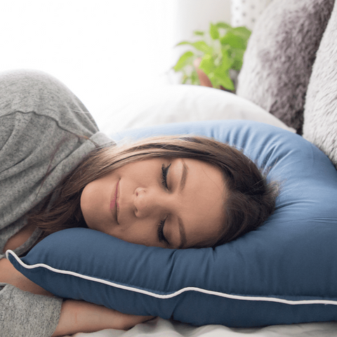 A woman resting peacefully on a cozy blue Pillowtex Dream in Color pillow.
