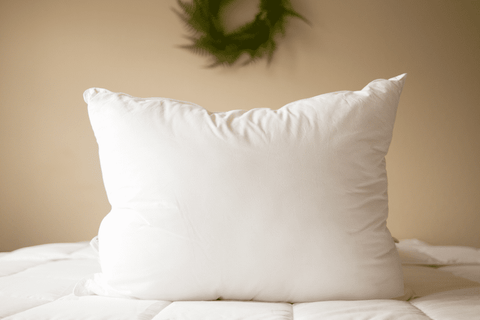 A Pillowtex Premium Polyester Pillow by Pillowtex on a bed with a wreath.