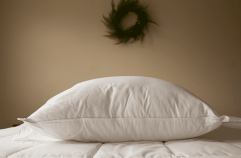 A Pillowtex Premium Polyester pillow rests on top of a bed with a wreath.