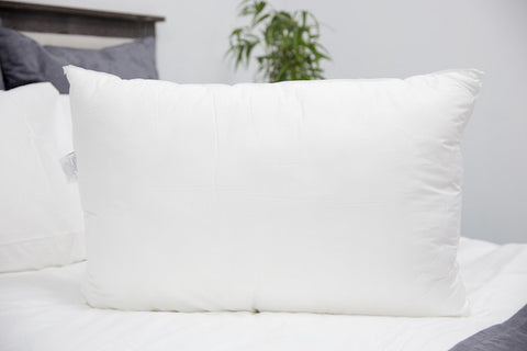 A fluffy white Pillowtex Like Down Pillow on the bed.