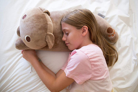 A girl peacefully sleeps with a Snuggle Pillow with Paws and Tail, a quality construction children's gift from Pillowtex.