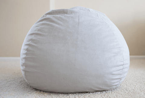 A Pillowtex memory foam bean bag chair rests on the plush carpet in the room.