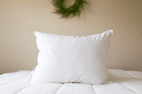 A Pillowtex Triple Core Lyocell Pillow rests on a bed adorned with a wreath.