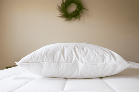 A Pillowtex Triple Core Lyocell Pillow on a bed with a wreath.