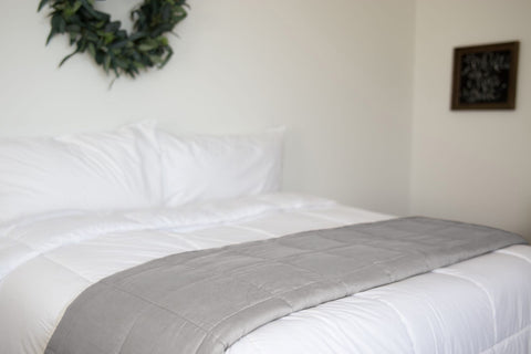 A Pillowtex Weighted Blanket with a white comforter and a wreath on it made of cotton.