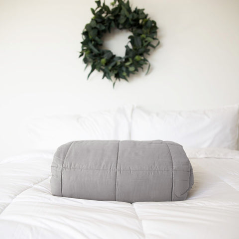 A Pillowtex Weighted Blanket on a white bed with a wreath of glass beads.
