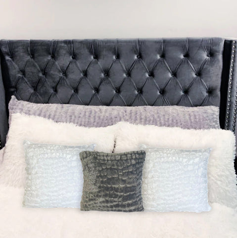 A bed with a tufted headboard and Pillowtex Plush 18'x18' Throw Pillows.
