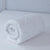 A white comforter on top of a Down Etc. Lily-Pad Waterproof Mattress Pad.