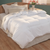 A white Pillowtex Arctic Weight Feather and Down Comforter rests on the wooden floor of a bedroom.